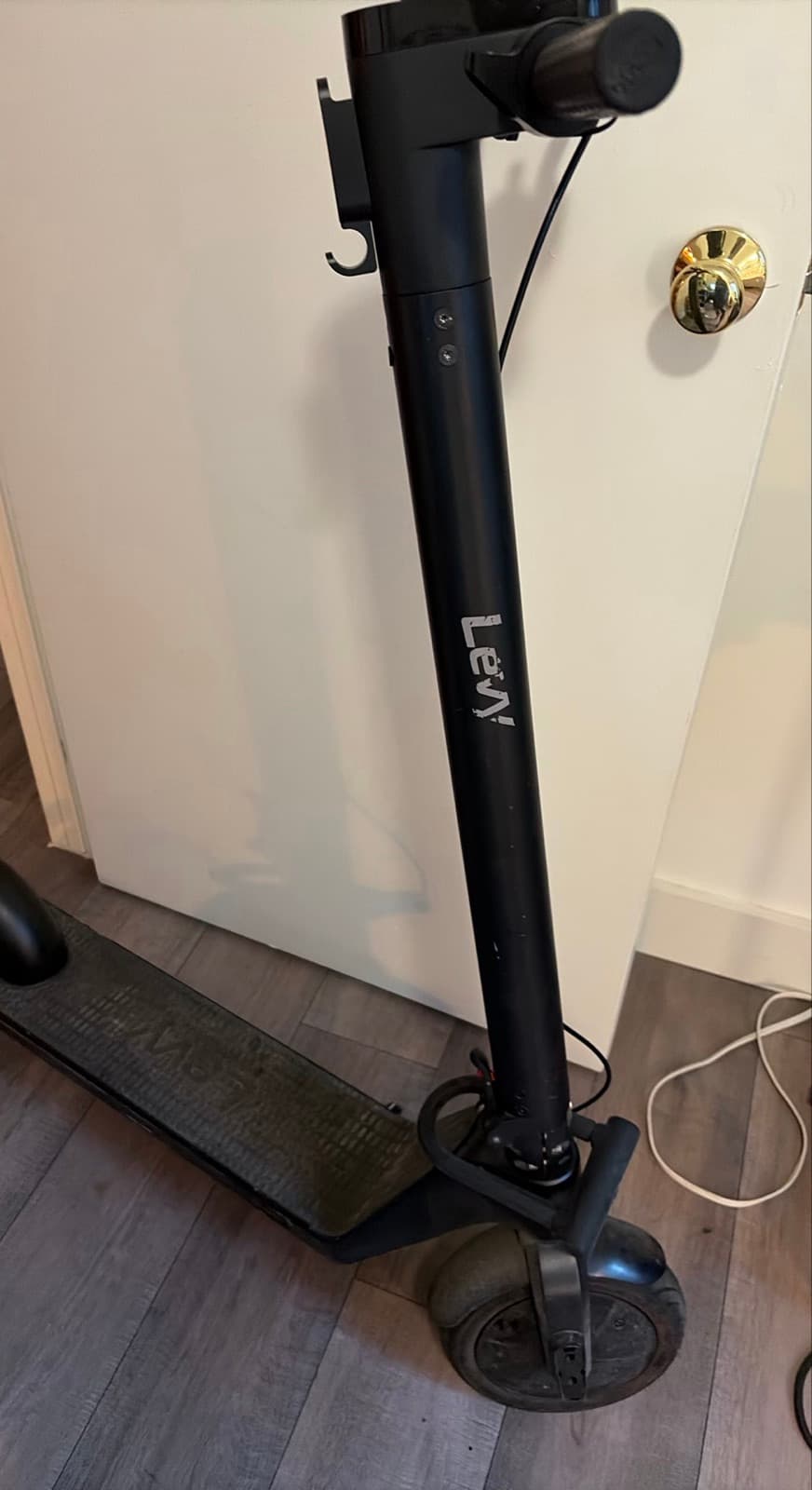 A scooter taken indoors and stood against an apartment door — a violation of a no-indoor-parking rule